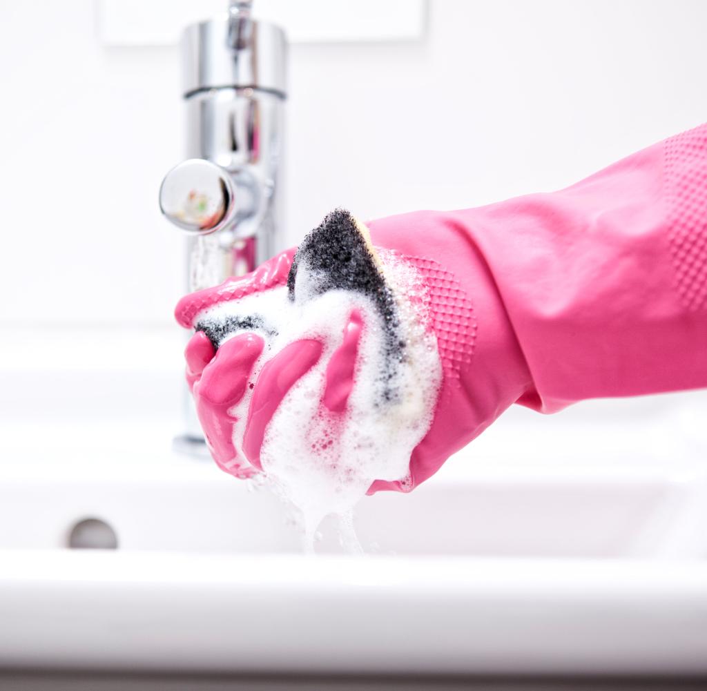 Woman cleaning the bathroom basin with a sponge