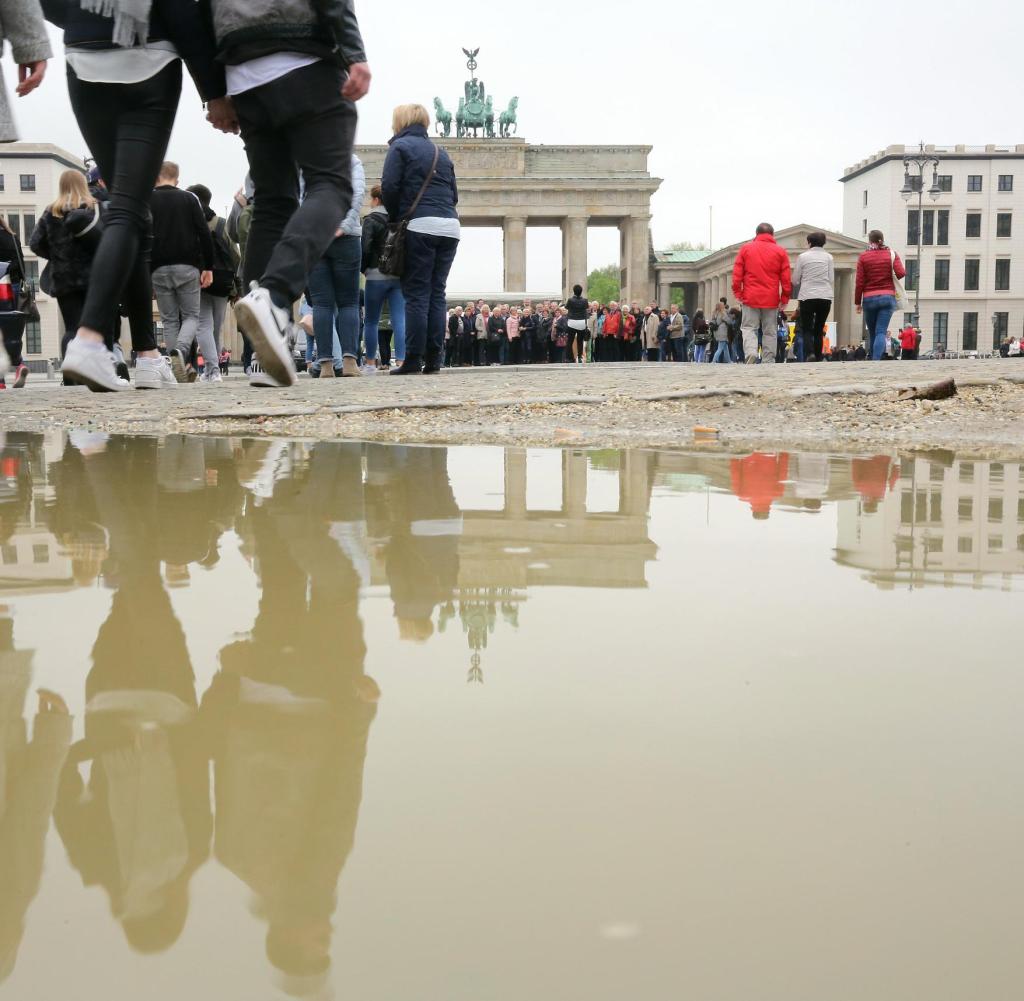Puddles of rain, in which tourists reflect in front of Berlin's Brandenburg Gate, dominate the image in front of the capital's landmark on May 5, 2017, at temperatures close to nine degrees Celsius.  Photo: Wolfgang Kumm / dpa +++ (c) dpa - Bildfunk +++