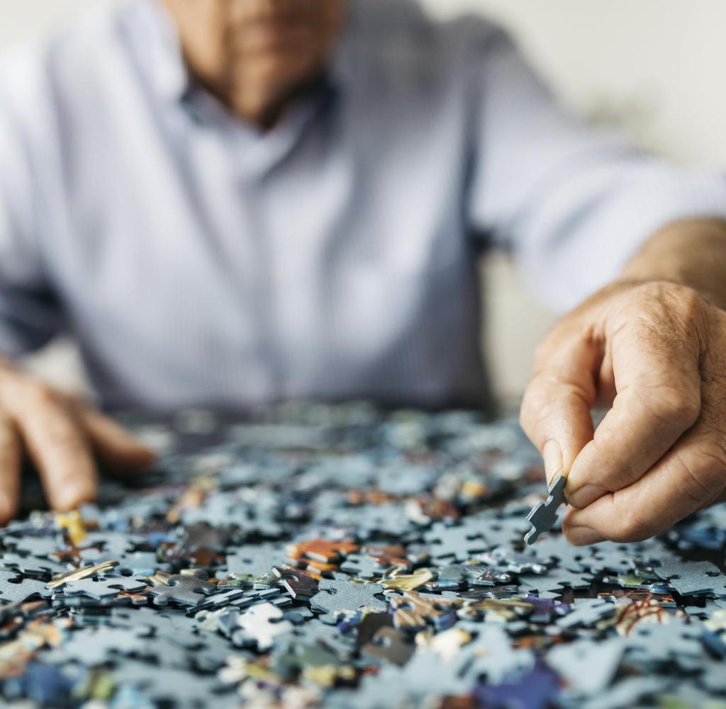 Senior retired man doing a puzzle, only hands.