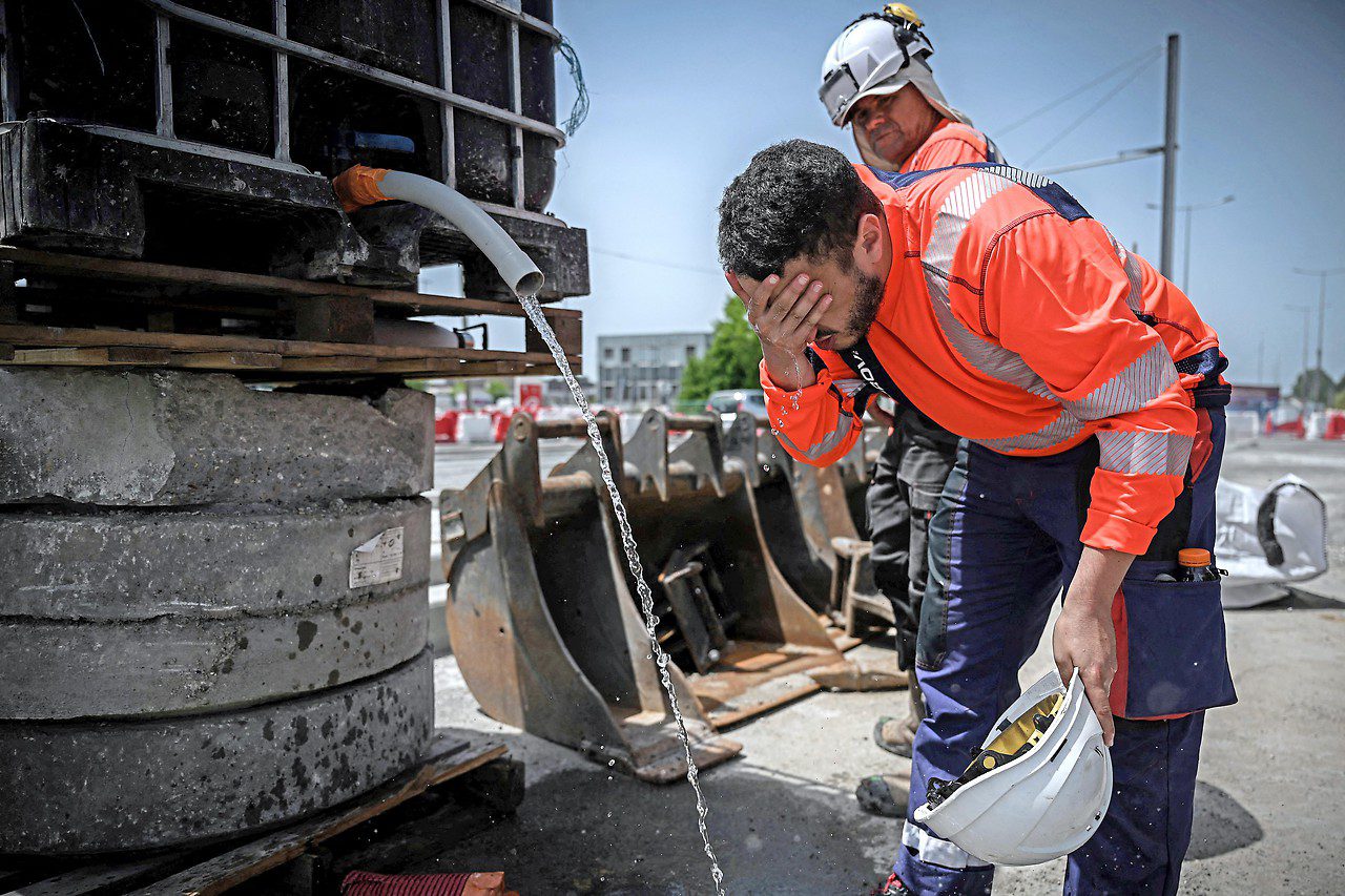 French workers refresh themselves in the heat at the water pipe